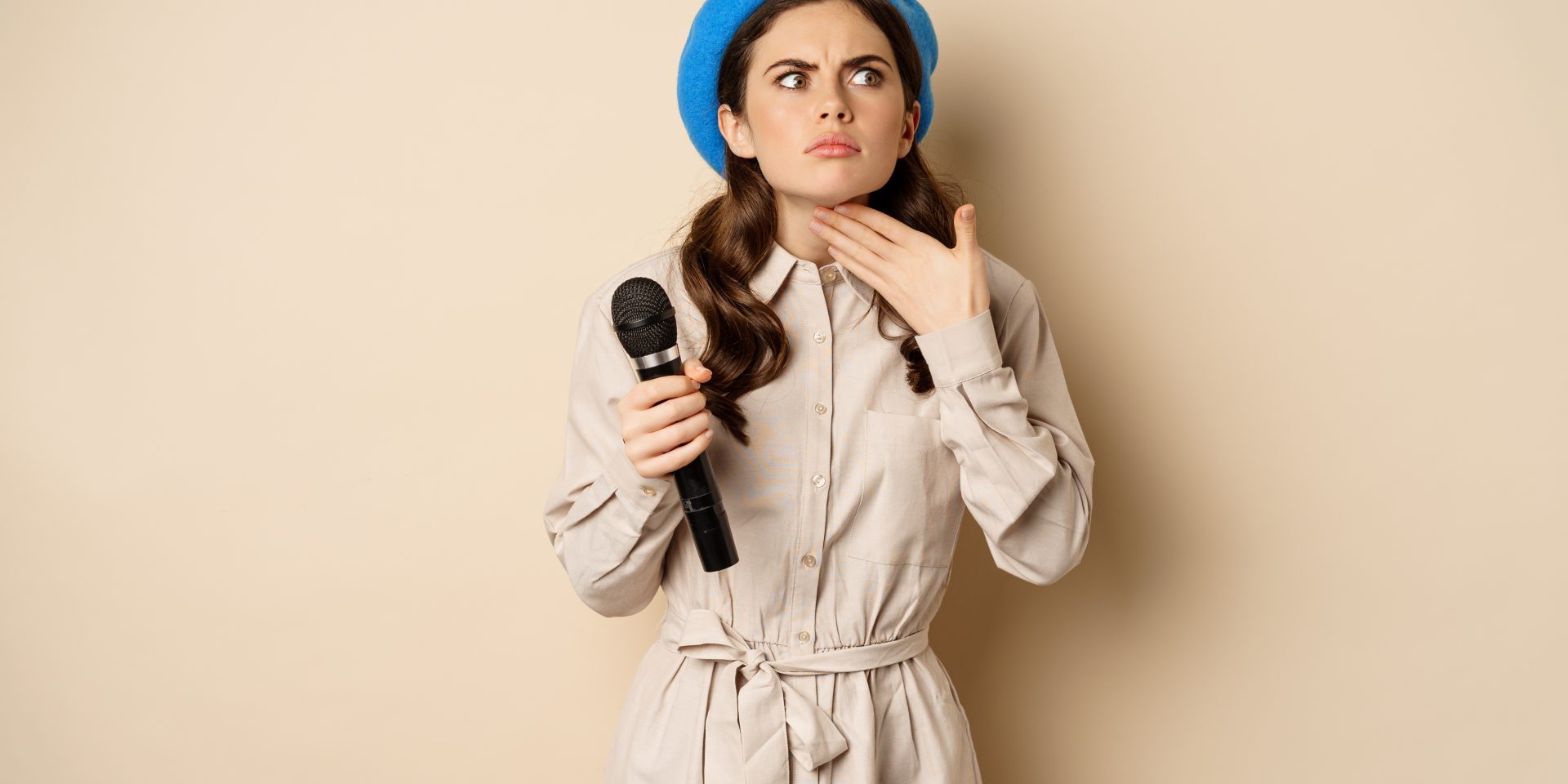 stylish-singer-woman-with-microphone-touching-throat-feeling-ill-standing-beige-background-copy-space tone of voice